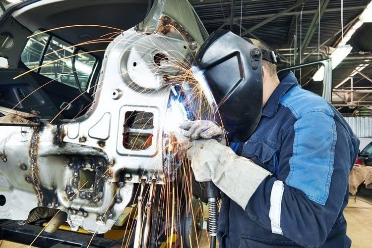 mechanic wearing face shield welding metal car parts